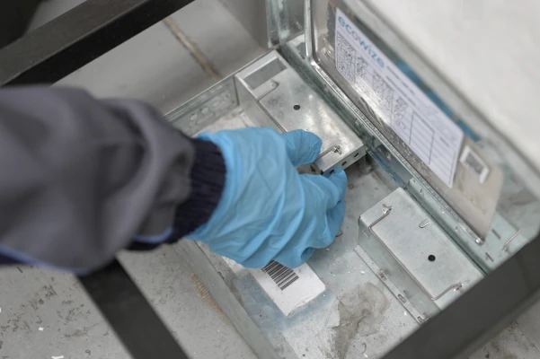 Technician wearing blue gloves servicing an Ecowize bait station, ensuring effective pest control maintenance and hygiene compliance.