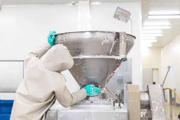 Food processing worker in protective clothing cleaning industrial equipment with a foaming sanitation solution.