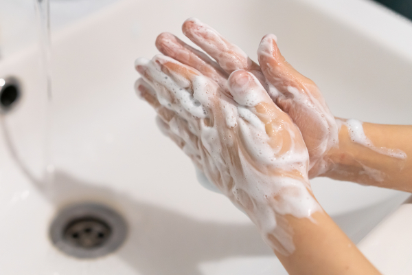 Hands covered in soap being washed under running water in a sink